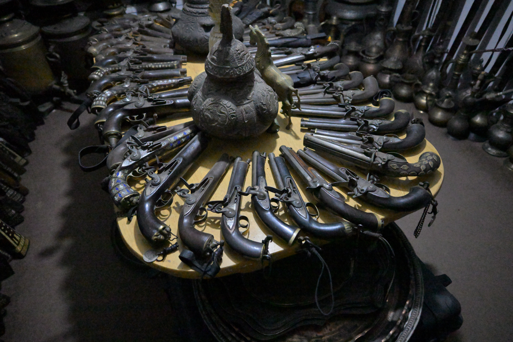 A fanned display of antique daggers and metalwork, raking light across old steel.